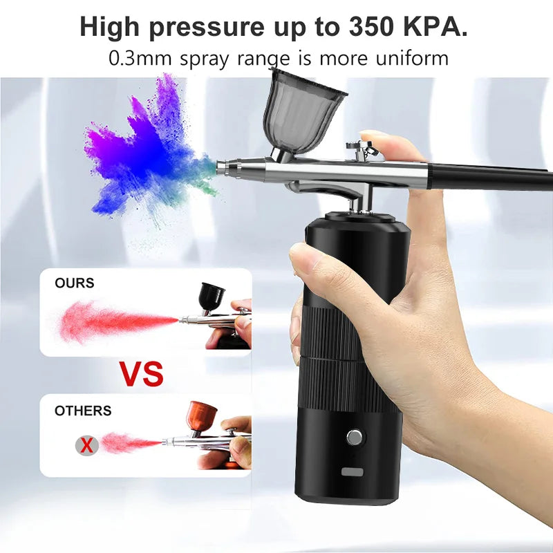 A hand holds a black mini air compressor nail art spray tool, demonstrating a uniform spray of purple paint.