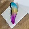 A glossy, iridescent purple and blue detangling hair brush lying on a white surface.