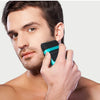 A man is using a black and teal electric hair trimmer on his face.