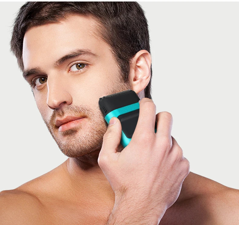 A man is using a black and teal electric hair trimmer on his face.