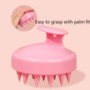 Brosse à cuir chevelu en silicone rose avec design de paume, montrée à côté d'une main.