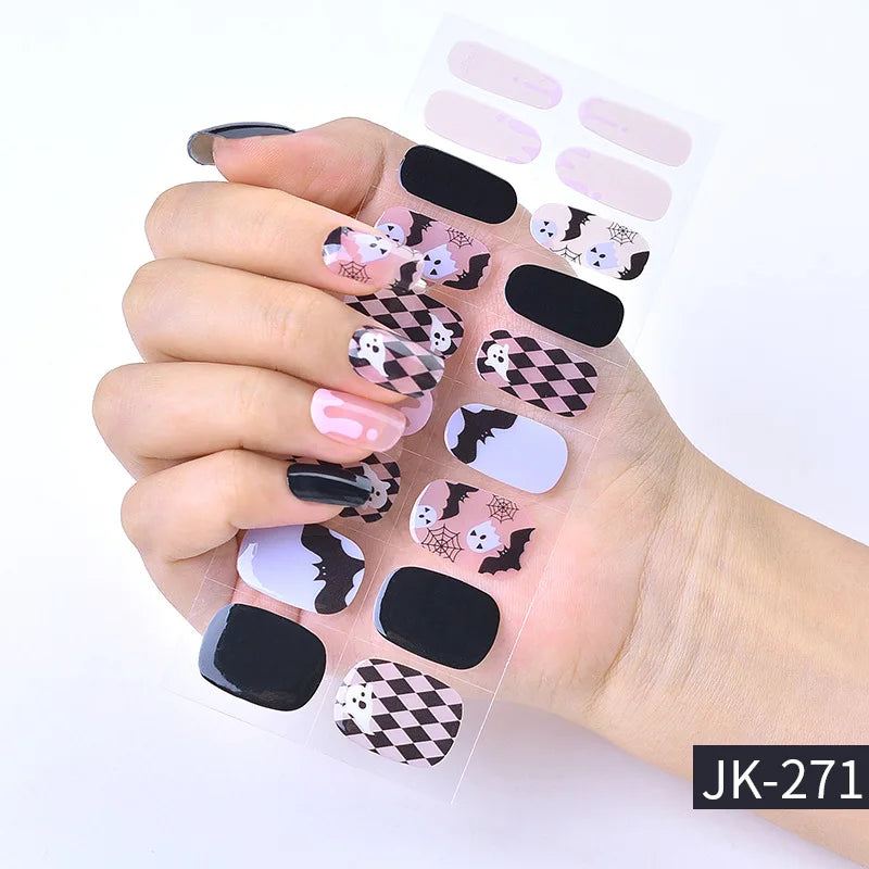 A hand displays Halloween UV gel nail stickers featuring bats, spiders, and checkered patterns on the nails.