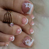 A close-up of a hand displaying press-on fake nails with short square French designs and floral accents.