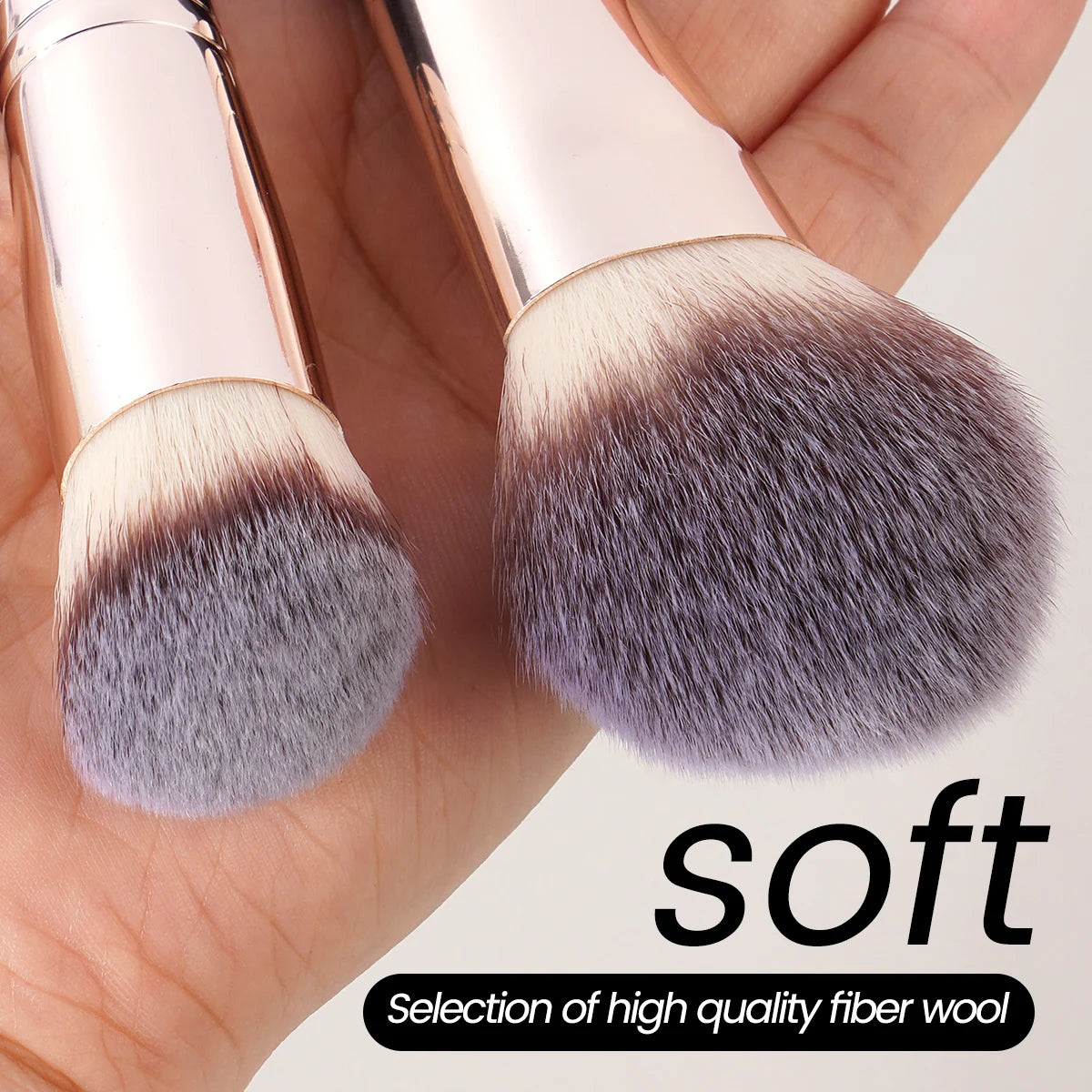 A close-up of a makeup brush showing soft gray and brown bristles on a wooden handle.