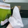 A white soft cotton disposable face towel is held against a green box with Chinese text.