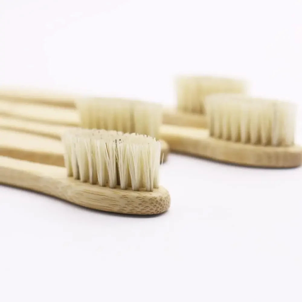 A wooden toothbrush with natural bamboo bristles is shown on a white background.