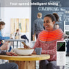 A woman is using an electric heated neck and shoulder massager while sitting at a table in a co-working space.