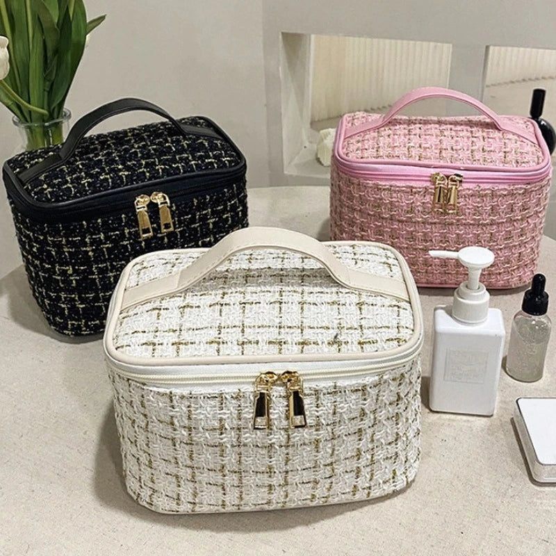 A collection of three knitted canvas makeup pouches in black, pink, and cream resting on a light surface.