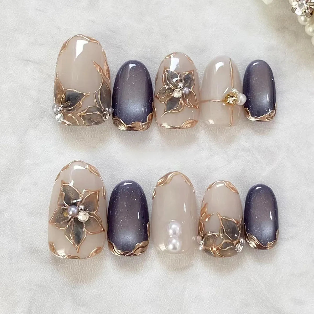 A set of 24 almond press-on nails featuring a glossy gray finish with gold floral and butterfly designs.