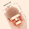 Une main tient un pinceau de maquillage Kabuki extra-large montrant sa taille et sa texture.