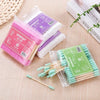 Une collection de cotons-tiges en bambou rose, violet et vert pour un nettoyage doux sont exposés sur une surface claire.