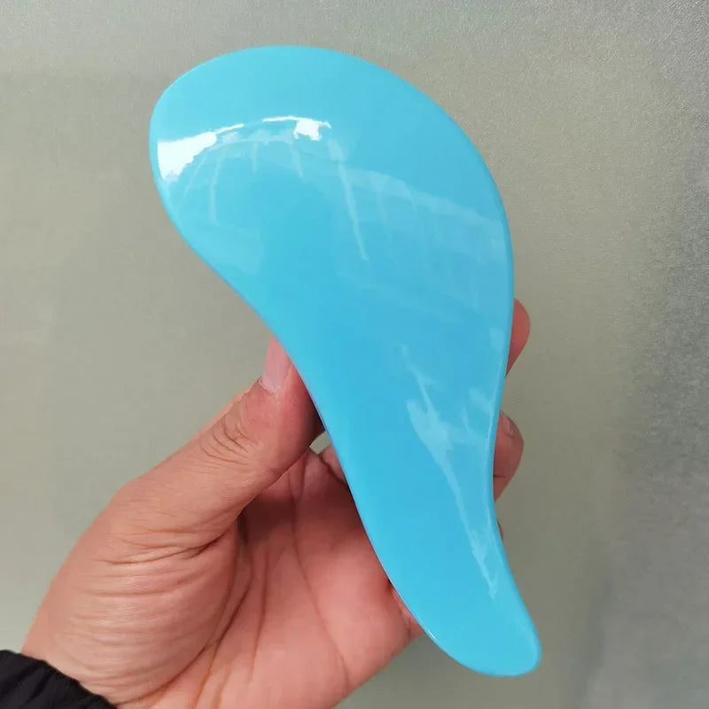 A hand holds a bright blue classic detangling hair brush against a light background.