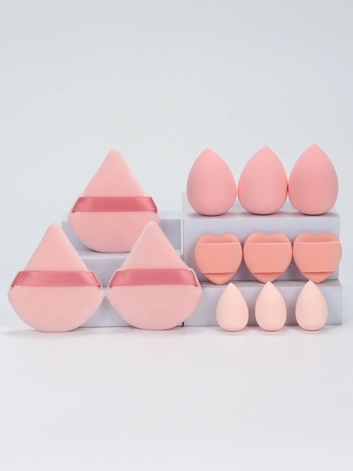 A set of twelve pink makeup sponges arranged in rows on a white surface.