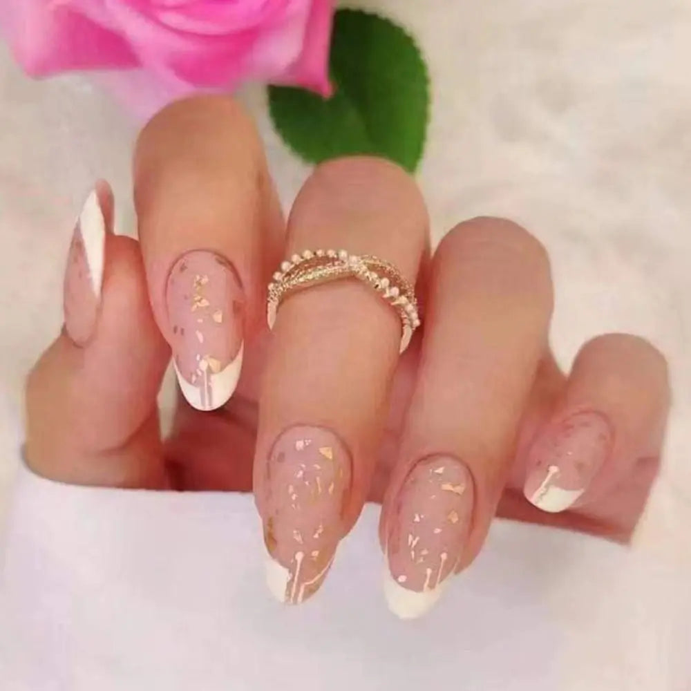 A hand displaying press-on false nails with a French wavy design and gold accent rings against a soft background.