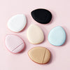 Collection de moussages de maquillage ronds dans diverses couleurs, y compris noir, blanc, beige clair et bleu clair, sur fon