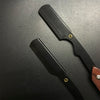 Afeitadora profesional manual negra con mango de madera sobre una superficie oscura.