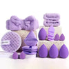 A set of purple beauty sponges and exfoliating pads stacked on a white surface.