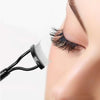 A close-up of a black precision metal eyelash separator and curler being used on a person's eye.