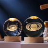 A glass crystal ball containing a swirling galaxy night light resting on a wooden base.