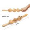 A natural wood gua sha roller with a handle and multiple rounded stones, shown being held by a hand.