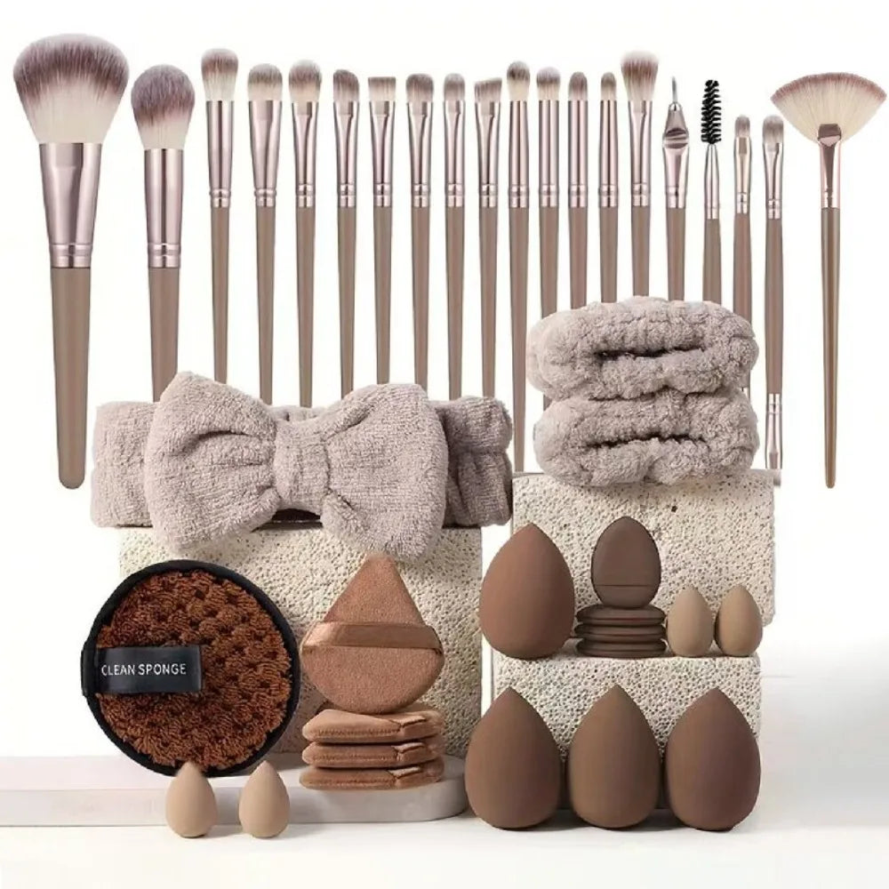 A collection of makeup brushes and tools in various sizes and shades displayed on a white surface.