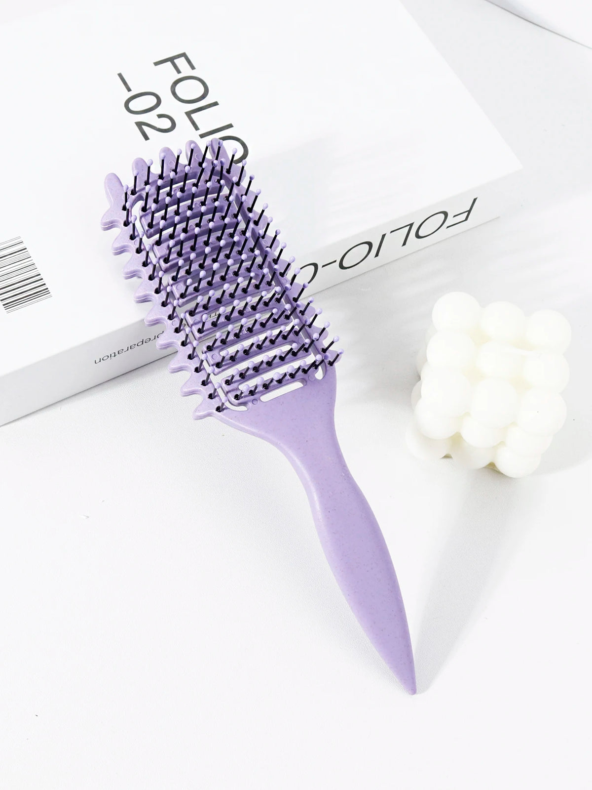 Peigne pour cheveux bouclés violet professionnel avec manche en plastique, à côté d'une boîte blanche.