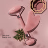 A pink resin facial massage roller set with a metal handle and a hexagonal wooden tool is shown on a light background.