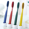 Un set de cinq brosses à dents colorées et douces, bleues, rouges, vertes et jaunes, sur une surface blanche.