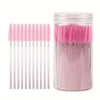 A glass jar filled with pink disposable eyelash and eyebrow makeup brushes.
