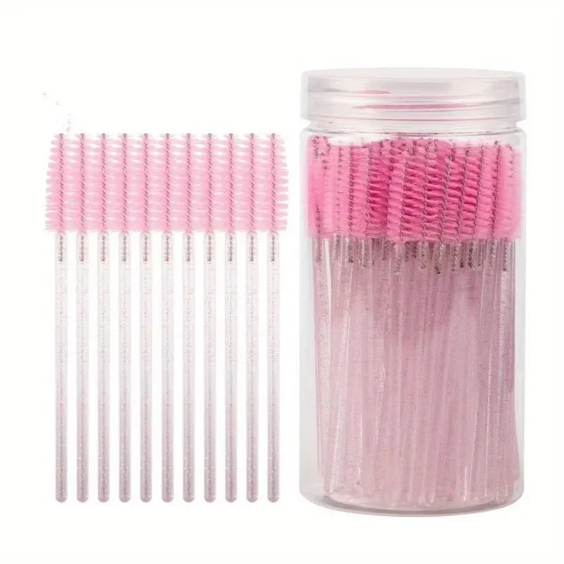 A glass jar filled with pink disposable eyelash and eyebrow makeup brushes.
