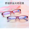 Pair of pink-framed reading glasses with purple patterned lenses shown against a light background.
