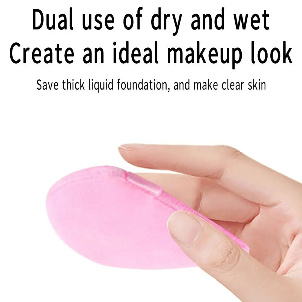 A hand holds a pink makeup sponge for applying liquid foundation or skincare.