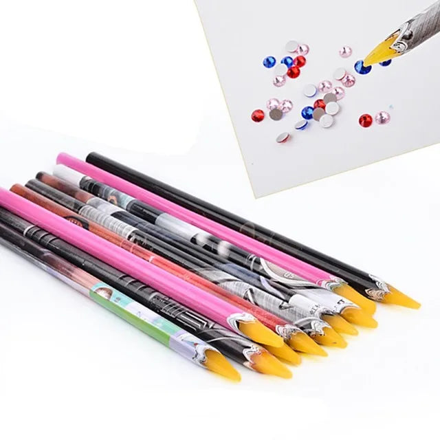 A set of nail art rhinestone wax picker pencils with various colored tips and a loose pile of rhinestones