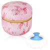 Éponge de maquillage portable rose rond avec garniture dorée à côté d'un applicateur blanc duveteux.