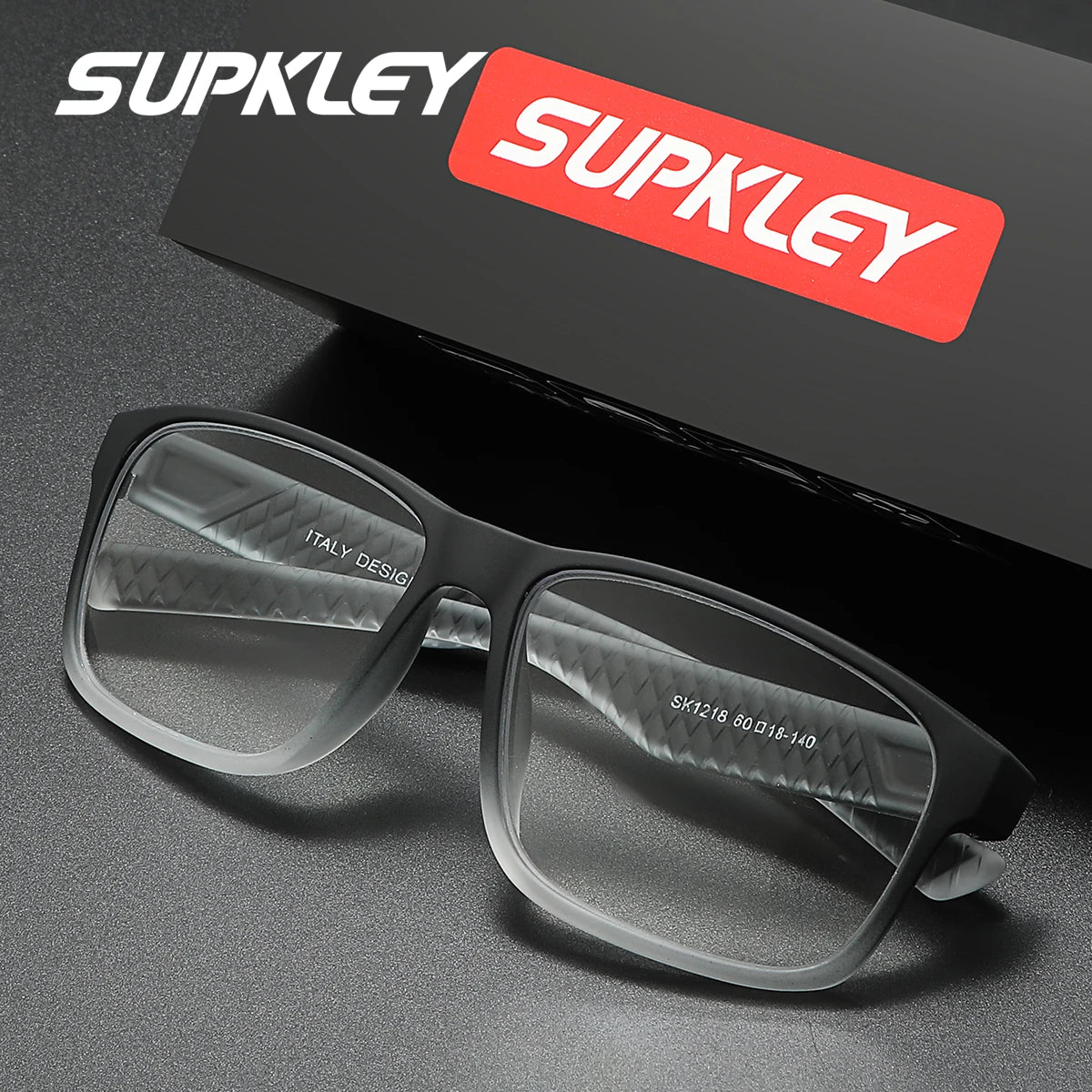 A pair of gray rectangular eyeglasses resting on a dark surface with a red Supkley logo box in the background.