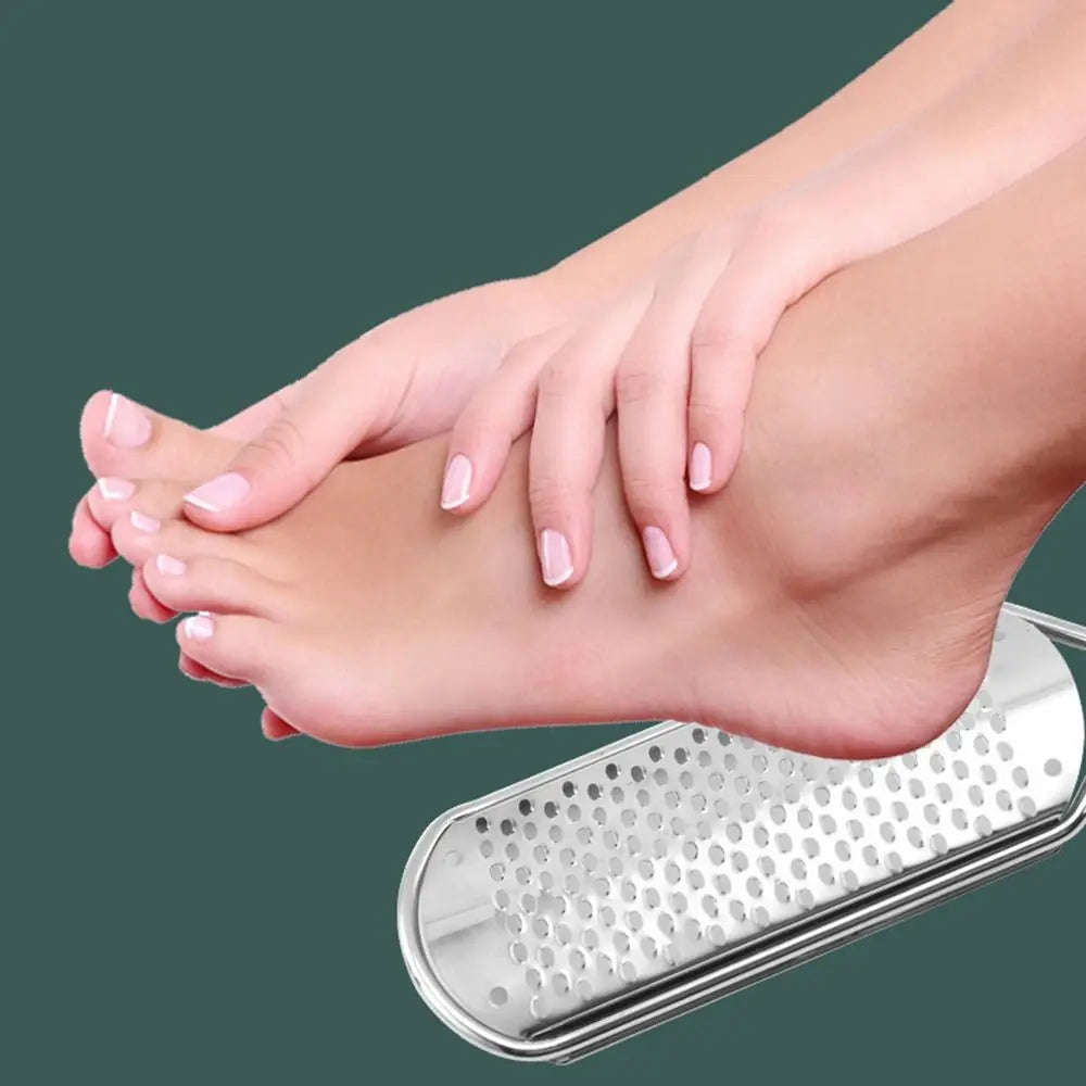 A hand is using a stainless steel foot file to remove calluses from the sole of the foot.