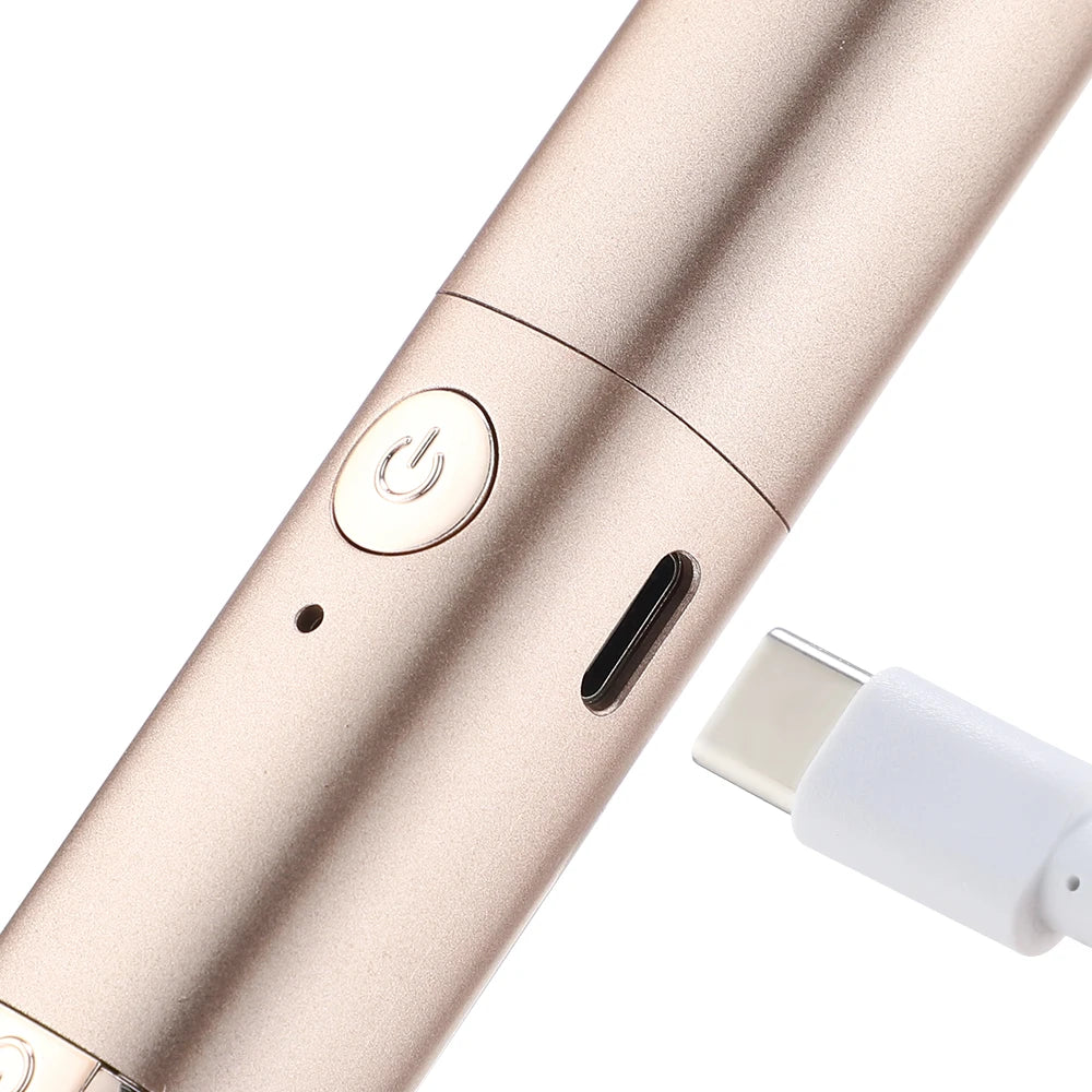 A close-up view of a rose gold electric heated eyelash curler and eyebrow trimmer with a charging port.
