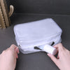 A hand is opening a clear waterproof travel cosmetic bag to reveal white makeup products.