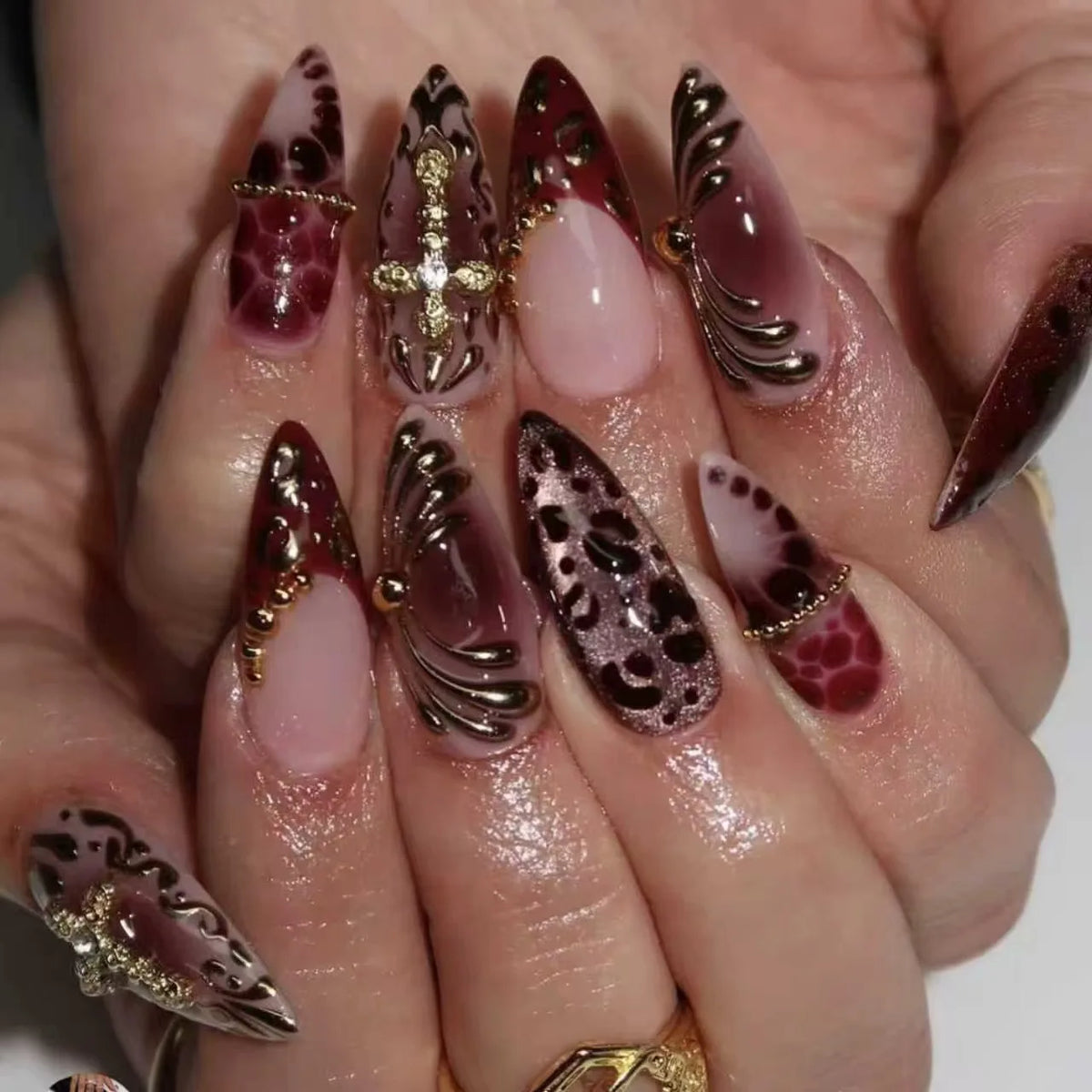 A close-up of a hand displaying 24 press-on nails featuring pink and brown floral designs.