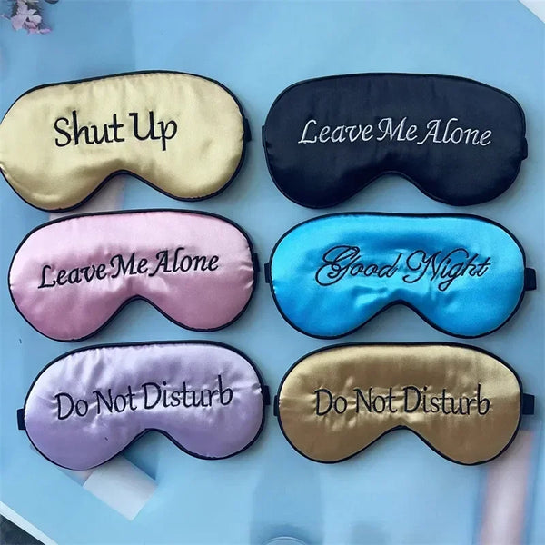 Four embroidered silk sleep masks in various colors including gold, black, pink, and blue.