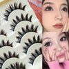 A collection of black false eyelashes in various styles and lengths displayed on a white tray.