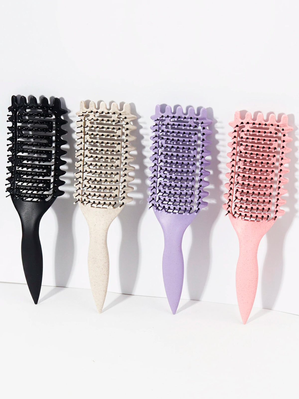 Un set de quatre peignes professionnels pour cheveux bouclés, de couleur noire, beige, violette et rose.