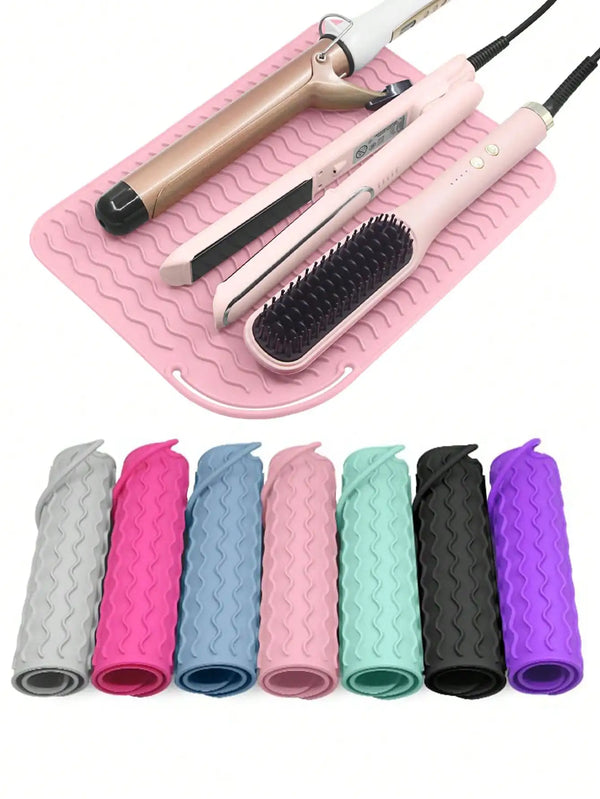 A pink silicone mat holds various hair styling tools including a curling iron and a brush with different colored silicone hai