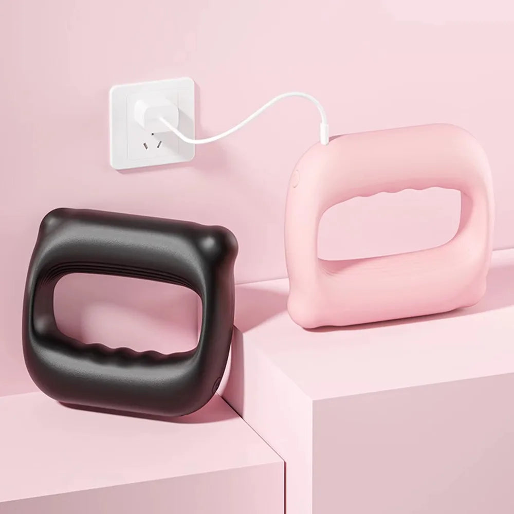 A pink portable electric fascia massager belt is shown next to a black version and a white power cord on a light pink surface