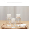 Clear glass refillable push-down pump dispenser bottles sitting on a wooden tray.