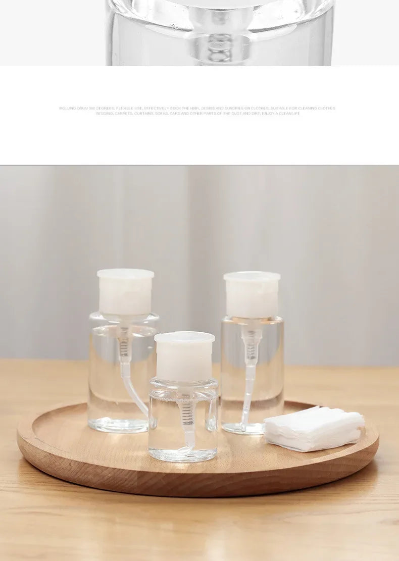Clear glass refillable push-down pump dispenser bottles sitting on a wooden tray.