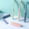 A collection of portable folding hairbrushes in pastel green, beige, and purple are displayed on a white surface.