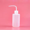 A clear plastic bottle for eyelash extension cleaning with a curved applicator brush against a pink background.