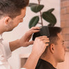 A man is using a black comb to style or detangle his hair.
