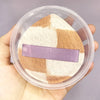 A cosmetic product featuring a beige and brown makeup puff set inside a clear plastic storage box.